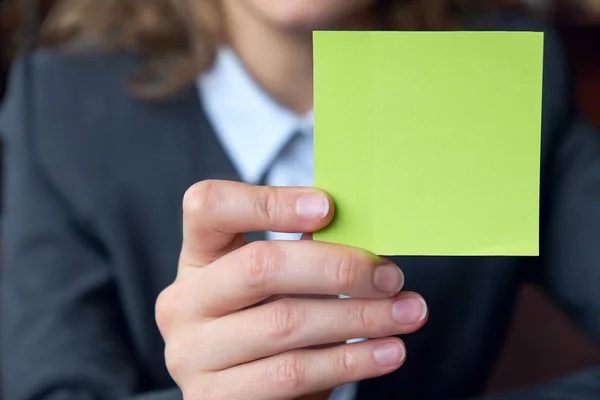 Business woman hand holding square blank clean sticker mock up. Close up background place for text