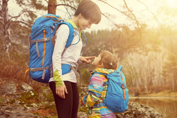 Hiking happy mother and little girl traveling with backpacks