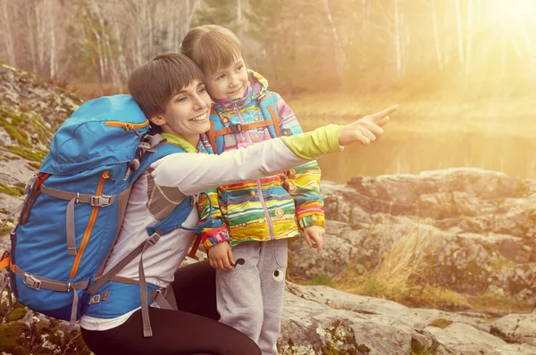 家族旅行 バックパックを持つ母親と子供は笑うと距離に指でポイント — ストック写真