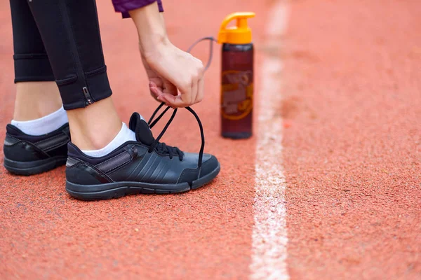 runner kadın çalışma parça Stadı şişe su ile yarış için hazırlanıyor koşu ayakkabıları dantel bağlama