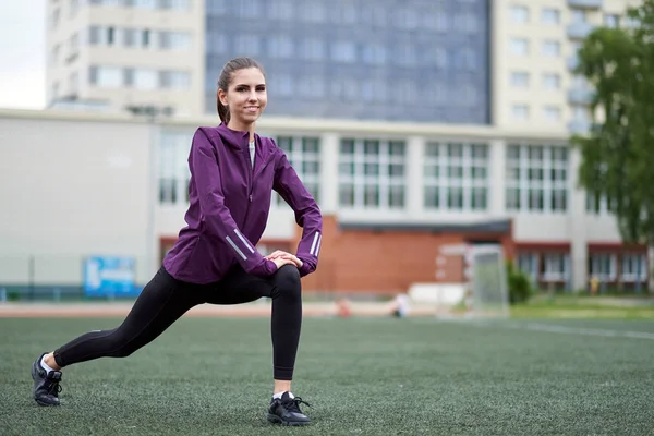 Onun bacak germe kadın ısınmak için uygun. Futbol sahasında
