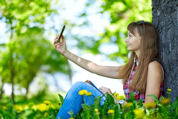 Bir akıllı telefon ile parkta güzel genç kadın selfie portresi
