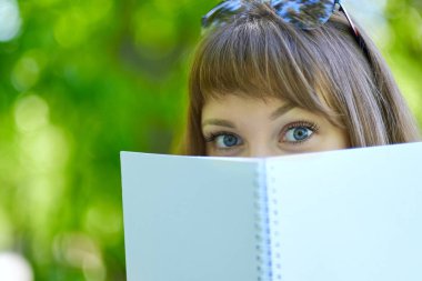 Mavi gözlü kız öğrenci bir kitap saklanıyor. Öğrenci kitap saklanıyor.