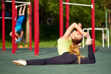 Esneyen jimnastikçi kadın spor sahasında iki büklüm oluyor..