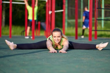 Esneyen jimnastikçi kadın spor sahasında iki büklüm oluyor..