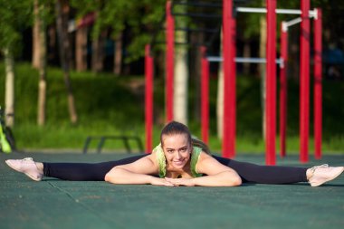Esneyen jimnastikçi kadın spor sahasında iki büklüm oluyor..