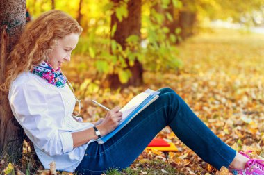 Kitaplar ve defter ve yazar ile Park'ın bahçesinde oturan genç öğrenci kadın