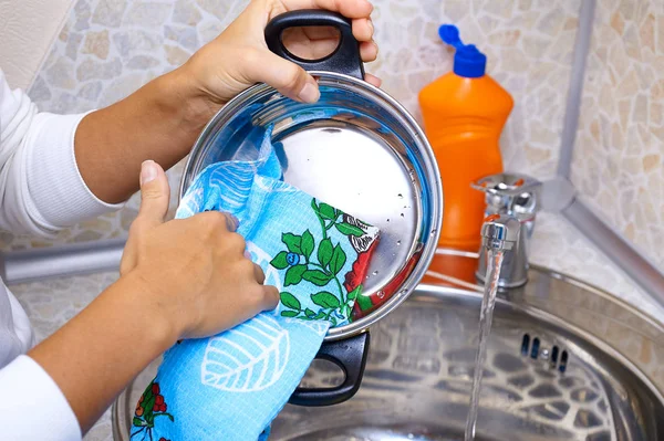 hands wipe pan with a towel. Wash dishes