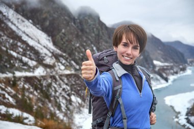 Sırt çantasıyla dağlarda gezen gülümseyen bir kadın. Güzel genç kız dağlarda geziyor.