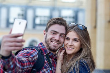 Şehrin gösteriş yerinde selfie çeken mutlu turistler. Kadın ve erkek şehrin arka planında fotoğraf çekiyorlar..