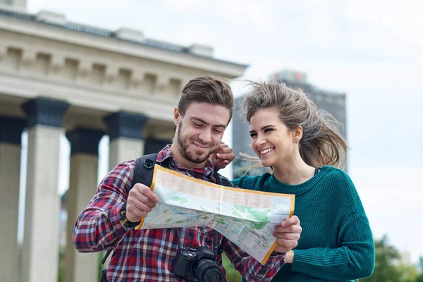 Young couple with a map in the city. Happy tourists sightseeing city with map.
