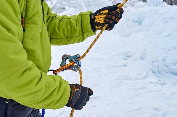 Ice climber belay with a rope and click up. hands close up. Providing safety.