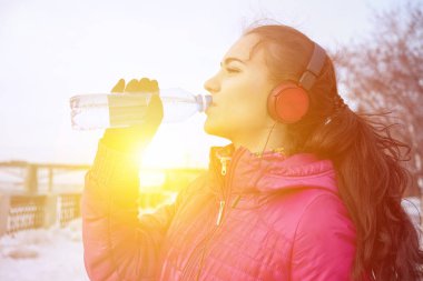 Drinking during sport. Young woman drinking water after run clipart