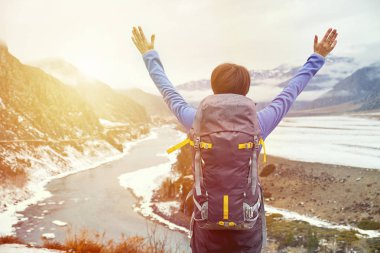 Gün batımında sırt çantalı bir kadın elini kaldırdı. Güzel genç kız dağlarda geziyor.
