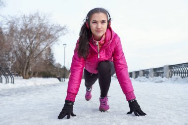 Mutlu genç kadın açık havada winter park, deniz kıyısında çalıştırmadan önce çalışma başlatmak hazırlanıyor