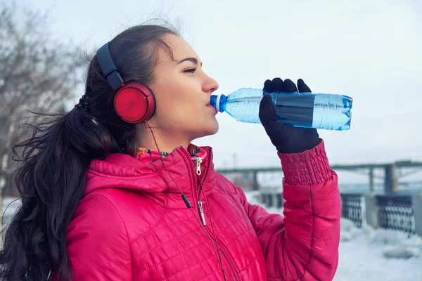 Spor sırasında içme. Genç kadın içme çalıştırdıktan sonra su