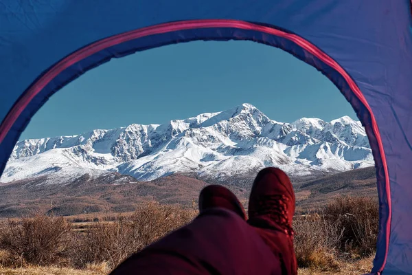 Tent lookout on a Camp in the mountains. Feet Hiker relaxing enjoying view from tent camping entrance outdoor. Travel Lifestyle concept adventure vacations outdoor.