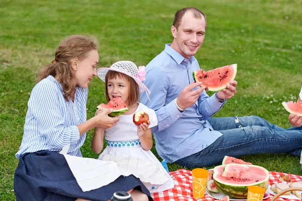 Piknikte karpuz yiyen mutlu bir aile. Anne, baba ve çocuk çayırda ya da parkta piknik yapıyorlar. — Stok fotoğraf