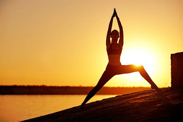 Siluet kadın yoga yapıyor ya da gün batımında ya da gün doğumunda sahilde geriniyor. — Stok fotoğraf