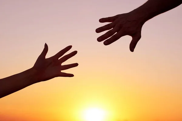 Echando una mano. Silueta Dos manos, hombre y mujer, que se acercan entre sí al atardecer del cielo — Foto de Stock