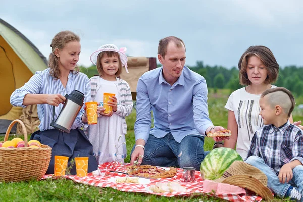 Famiglia felice che fa un picnic nel prato in una giornata di sole. Famiglia Godersi una vacanza in campeggio in campagna — Foto Stock