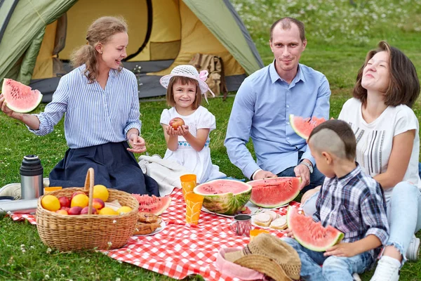 Mutlu bir aile çadırın yanındaki çayırda piknikte karpuz yiyor. Aile Kırsalda Kamp Eğlencesi Tatili — Stok fotoğraf