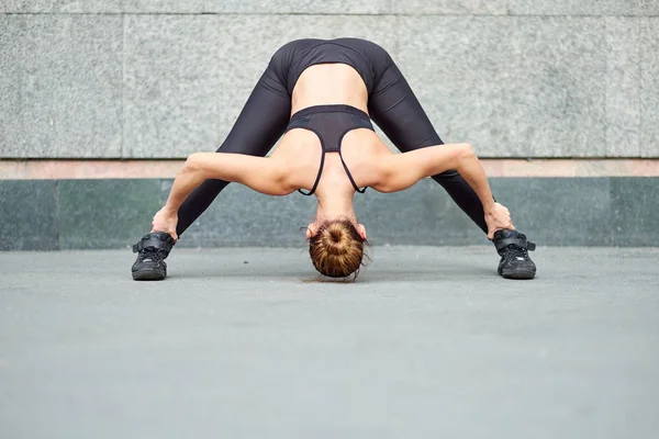 Mujer estirada. fitness o gimnasta o bailarina haciendo ejercicios sobre fondo de pared gris —  Fotos de Stock
