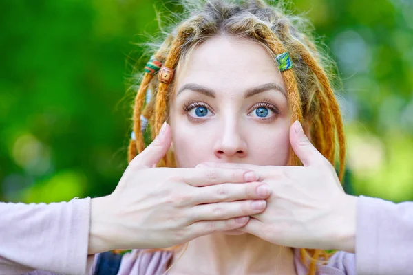 Woman close your mouth with your hands. Silence, gesture, no gossips, secret. Portrait in summer green park