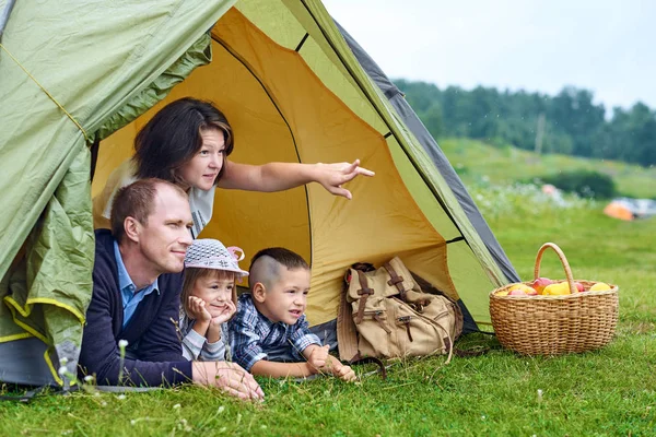 Padres de familia y dos niños en la tienda de campaña. Feliz madre, padre, hijo e hija en vacaciones de verano. Mamá mostrando algo en la distancia — Foto de Stock