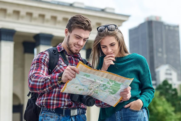 Pareja joven con un mapa en la ciudad. Felices turistas turismo ciudad con mapa — Foto de Stock
