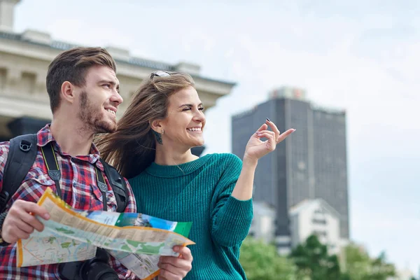 Pareja joven con un mapa en la ciudad. Felices turistas turismo ciudad con mapa — Foto de Stock