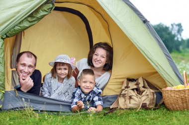 Aile ve iki çocuk kamp çadırında. Mutlu anne, baba, oğul ve kız yaz tatili