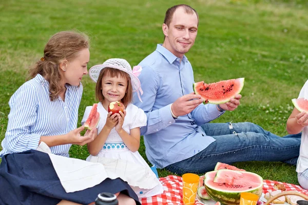 Piknikte karpuz yiyen mutlu bir aile. Anne, baba ve çocuk çayırda ya da parkta piknik yapıyorlar. — Stok fotoğraf