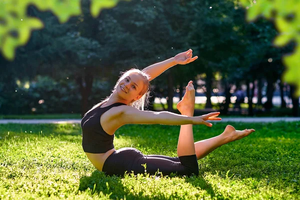 Yoga. Mujer joven practicando yoga o bailando o estirándose en la naturaleza en el parque. Concepto estilo de vida. — Foto de Stock