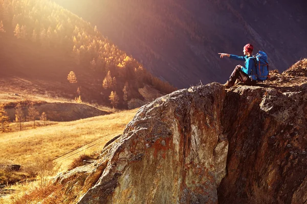 Mujer excursionista con mochila sentada en la roca de una montaña y disfrutando del amanecer — Foto de Stock