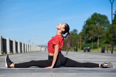 Esneyen jimnastikçi kadın kırışıyor, şehirde sicim yapıyor.