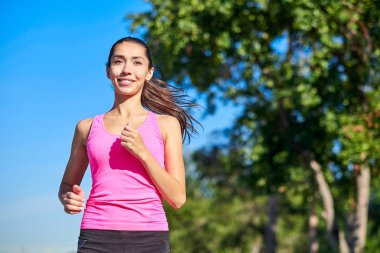 Genç fitness kadını orman yolunda koşuyor..