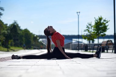 Esneyen jimnastikçi kadın kırışıyor, şehirde sicim yapıyor.