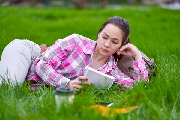 Jeune femme asiatique lecture livre couché sur herbe prairie — Photo