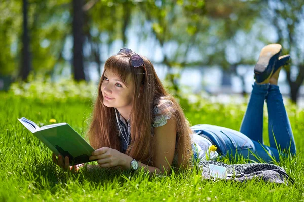 Nastoletnią student dziewczyna z książką w parku i leżąc na trawie — Zdjęcie stockowe