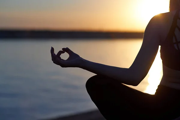 Siluet kadın yoga yapıyor ya da gün batımında ya da gün doğumunda sahilde geriniyor. — Stok fotoğraf