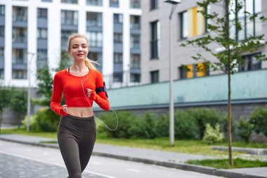 Kapüşonlu genç bayan koşucu şehir sokaklarında koşuyor.