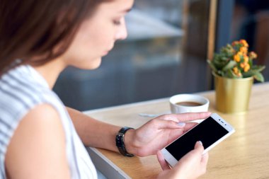 Akıllı telefonları, kulaklıkları ve bir fincan çayı olan kadın elleri. Grafik görüntüleme montajı için