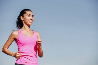 Koşan fitness kadını. Mavi arka planda pembe bluzlu bir kadın..