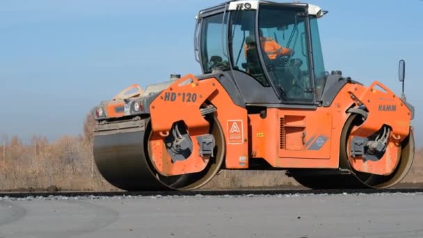 RUSSIA, Novosibirsk - May 30, 2020：Road construction works with roller compactor machine and asphalt finisher — 图库视频影像