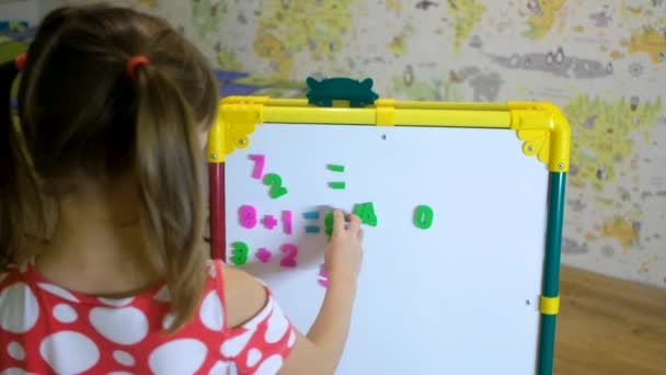 Mädchen lernt zu Hause mit Magnettafel Buchstaben und Zahlen — Stockvideo