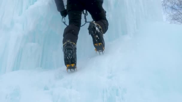 Steigeisen hautnah an den Füßen Eiskletterer auf einem gefrorenen Wasserfall. Eissplitter. — Stockvideo