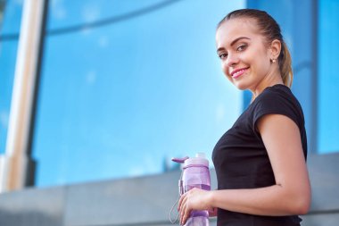 Spor salonunda antrenman yaptıktan sonra spor yapan kadın su içiyor..