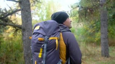 Sırt çantalı bir yürüyüşçü ormanda yürüyor. Sonbahar yürüyüşü