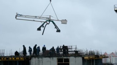 İnşaat işçileri yüksek binalarda beton örümcek hortumu ya da pompa kullanarak ıslak beton döküyorlar. Yağmurda çalışmak